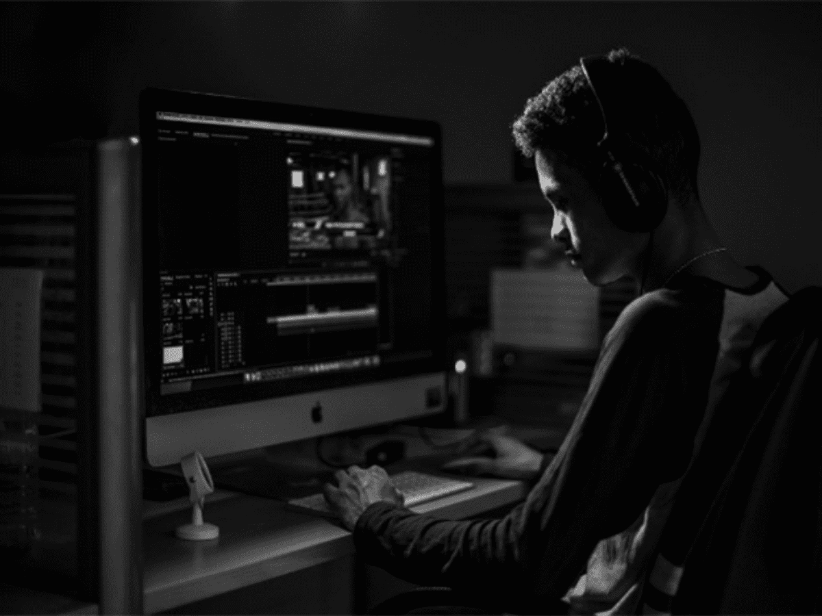 Black and white photo of a teenage boy sitting in front of a computer wearing headphones